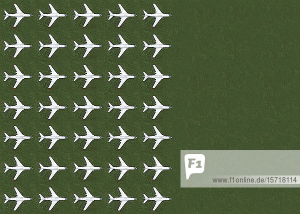 Aerial view of rows of airplanes standing on green grass