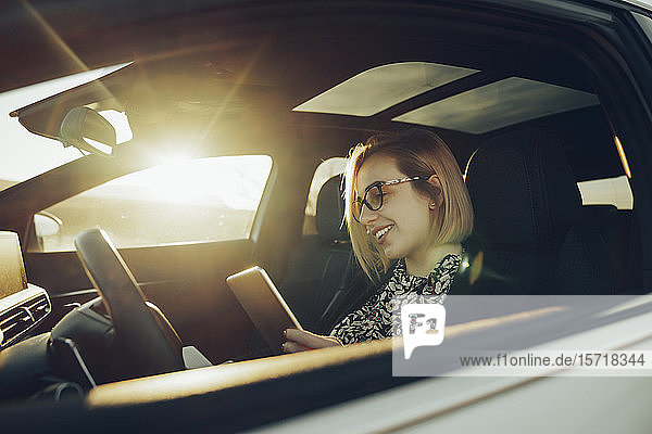 Young blond woman using smartphone in the car