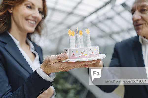 Geschäftsmann und Geschäftsfrau feiern Geburtstag im Amt mit gefälschtem Geburtstagskuchen