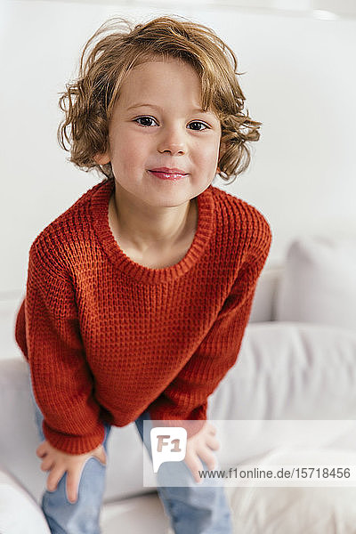 Porträt eines lächelnden Mädchens  das zu Hause auf der Couch steht