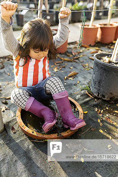 Kleines Mädchen mit Wellington-Stiefeln spielt im Höschen-Kindergarten