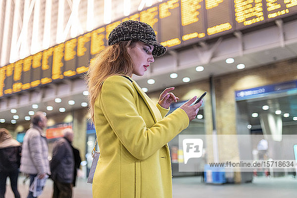 Woman at train station checking her smartphone