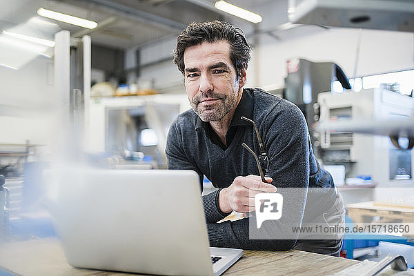 Porträt eines Geschäftsmannes mit Laptop in einer Fabrik