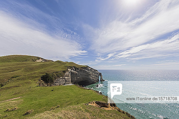 New Zealand  Sun shining over cliffs and natural arch of Cape Farewell headland