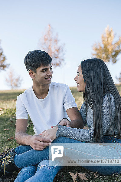 Verliebtes junges Paar sitzt im Herbst auf einer Wiese