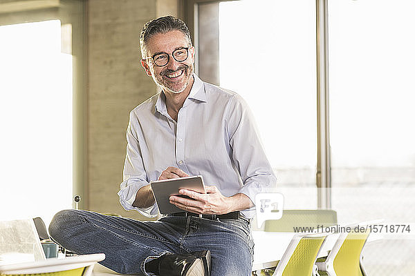 Glücklicher reifer Geschäftsmann mit Tablette im Büro