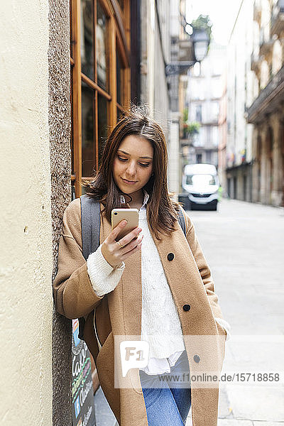 Young woman checking her phone in the city  Barcelona  Spain