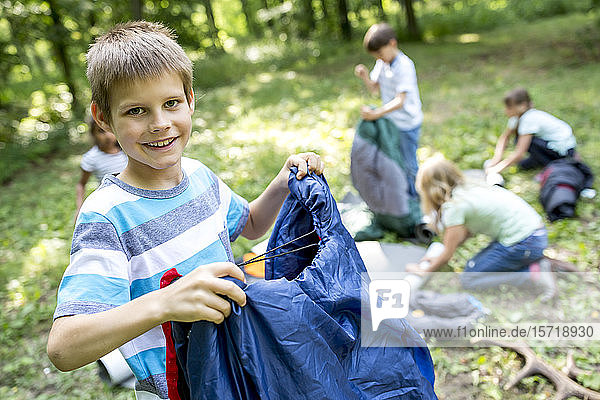 Schulkinder packen ihre Schlafsäcke aus  um im Wald zu campen