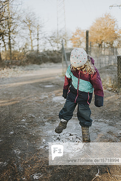 Girl kicking on frozen puddle