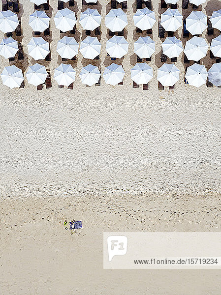 Indonesien  Bali  Luftaufnahme eines Mannes beim Sonnenbaden vor Reihen von Sonnenschirmen am sandigen Küstenstrand von Nusa Dua