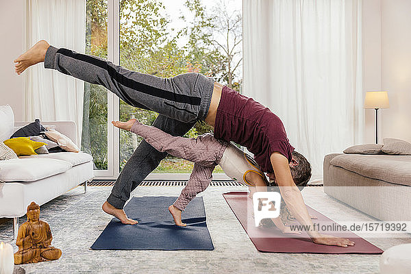 Father and daughter doing yoga together at home