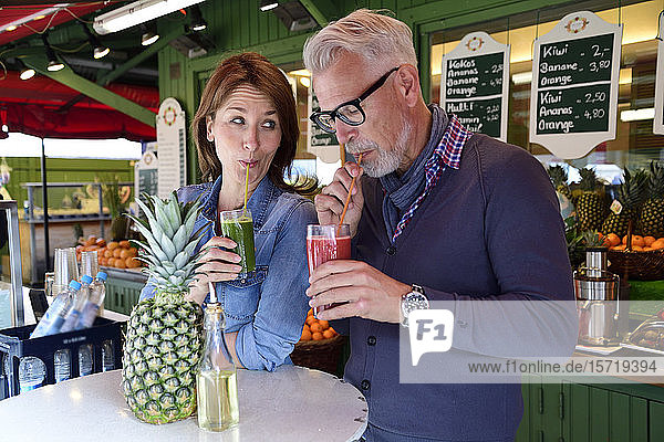 Ein reifes Paar trinkt einen gesunden Saft an einem Marktstand