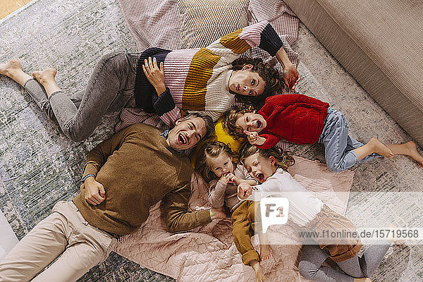Happy family with three daughters lying on blankets at home