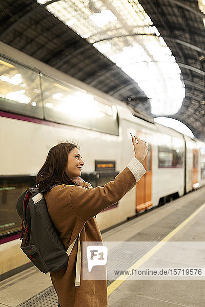 Junge Frau beim Selfie am Bahnhof