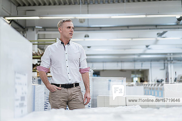 Mann mit weißem Hemd in einer Fabrik  der sich umsieht