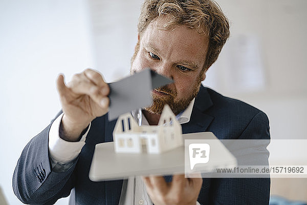 Geschäftsmann mit Modellhaus im Amt