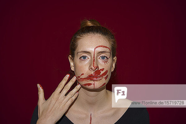 Porträt einer jungen Frau  die Farbe auf ihr Gesicht schmiert