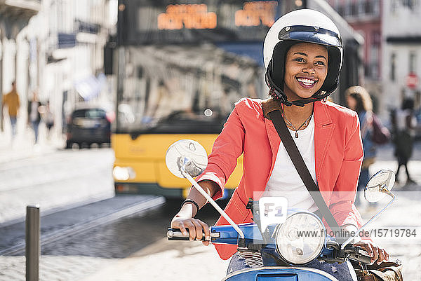 Glückliche junge Frau fährt Motorroller in der Stadt  Lissabon  Portugal
