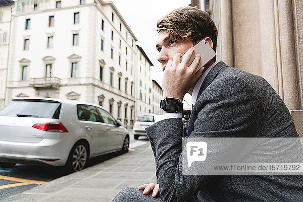 Junger Geschäftsmann mit Smartwatch am Telefon in der Stadt