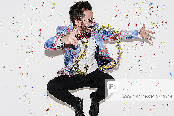 Stylischer Mann mit farbenfrohem Anzug und Sonnenbrille feiert eine Party und springt
