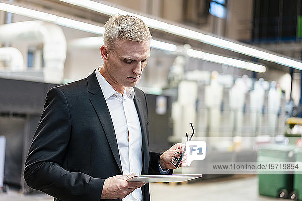 Businessman using a tablet in a factory