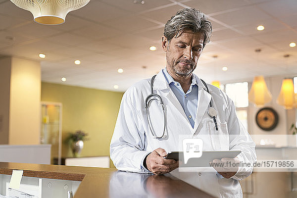 Arzt mit Tablette am Empfang in seiner Praxis