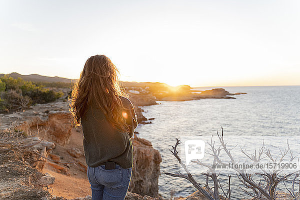 Rothaarige junge Frau steht bei Sonnenuntergang an der Küste  Ibiza  Spanien