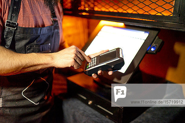 Young man  working in bar  using card reader