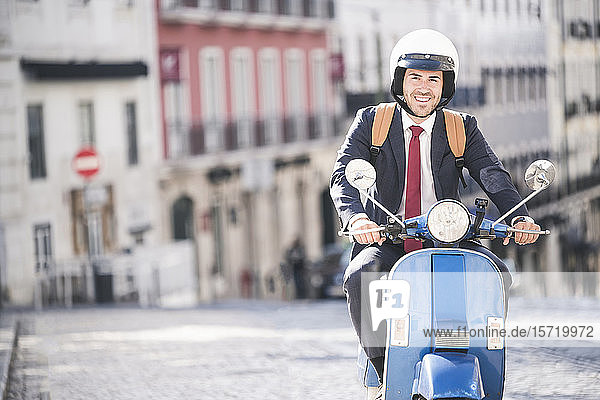 Porträt eines lächelnden jungen Geschäftsmannes auf einem Motorroller in der Stadt  Lissabon  Portugal