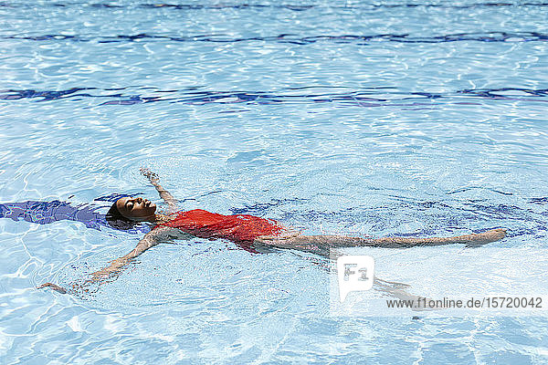 Young woman floating on water in swimming pool
