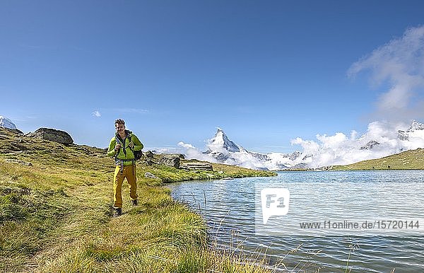 Hiker at Lake Stellisee  5 lakes Hiking trail  snow-covered Matterhorn at the back  Valais  Switzerland  Europe