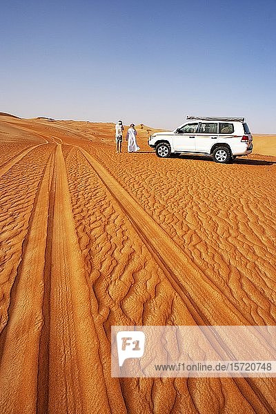 Reifenspuren im Sand  Tourist und Beduine stehen neben Geländewagen  Wüstensafari  Wüste Rimal Wahiba Sands  Oman  Asien