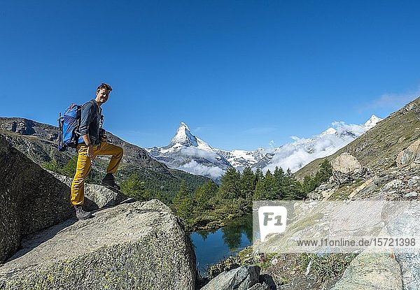 Hiker standing on rocks  behind Lake Grindij and snow-covered Matterhorn  Valais  Switzerland  Europe