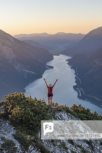 Sunset  young woman looking over mountain landscape stretches arms in the air  view from the mountain Bärenkopf to Lake Achensee  Tyrol  Austria  Europe
