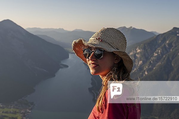 Junge Frau mit Sonnenbrille und Sonnenhut  im Hintergrund Berglandschaft mit Achensee  Blick vom Bärenkopf  Tirol  Österreich  Europa