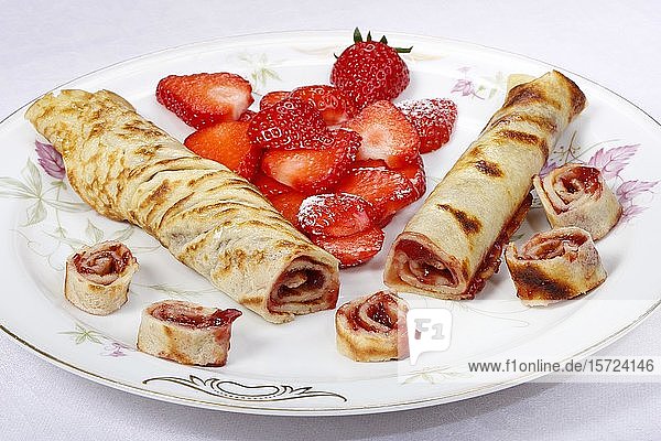 Dessert auf Teller  gefüllte Pfannkuchen mit Marmelade  Puderzucker und frischen Erdbeeren  gerollt auf einem Teller  Deutschland  Europa