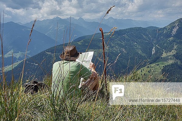 Hiker resting on alpine meadow with a view of the Lesach Valley and the Carnic Alps  Almgebiet Mussen  Carinthia  Alps  Austria  Europe