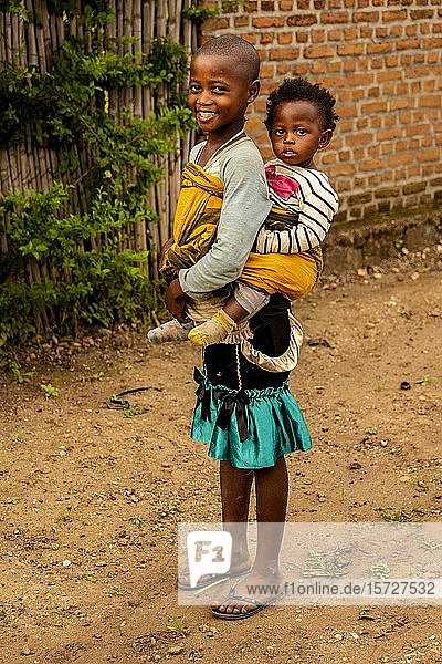 Lachendes Mädchen trägt ein Geschwisterchen auf dem Rücken  Rubona  Ruanda  Afrika
