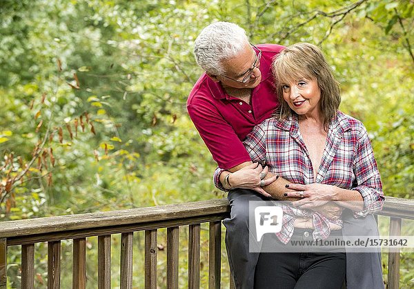 A mature couple outdoors  hugging  talking and laughing  looking at each other.
