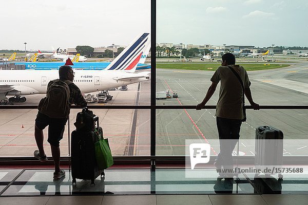 Singapore  Republic of Singapore  Asia - Two passengers look at parked aeroplanes on the apron from the Terminal 1 viewing mall at Changi Airport.
