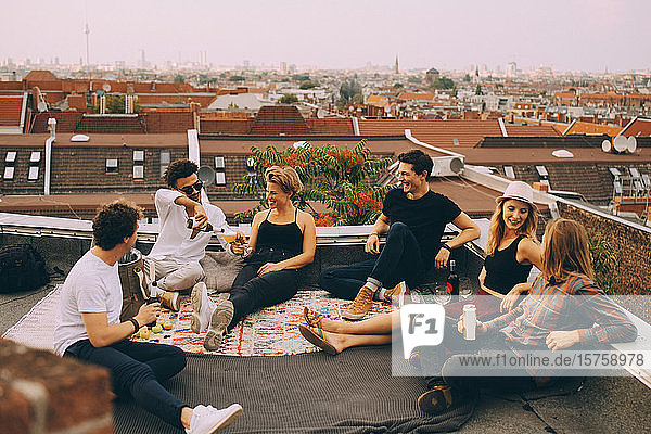 Fröhliche Freunde genießen Bier auf der Terrasse während einer Dachfeier in der Stadt