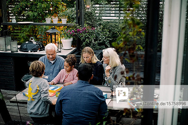 Schrägaufnahme eines Brettspiels der Familie auf dem Tisch  während sie auf der Terrasse sitzen