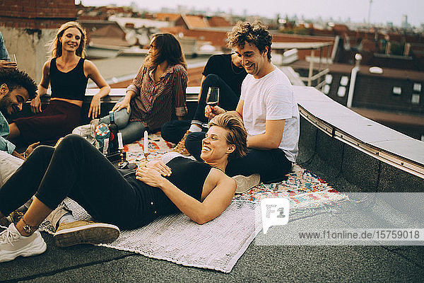 Fröhliche Freunde entspannen auf der Terrasse während einer Dachfeier
