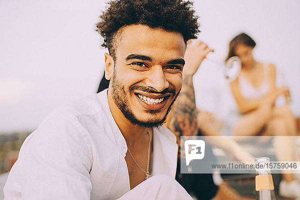 Porträt eines fröhlichen Mannes  der sich mit Freunden auf einer Dachfeier amüsiert