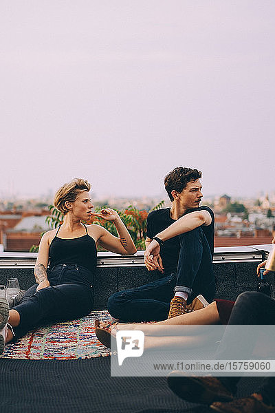 Freundinnen und Freunde schauen weg  während sie auf einer Terrasse in der Stadt zusammensitzen
