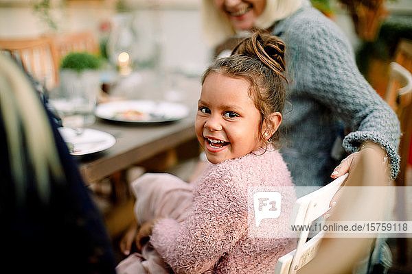 Portrait of smiling girl sitting with grandmother by dining table during lunch