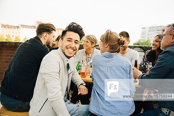 Porträt eines glücklichen Mannes  der mit Freunden zusammensitzt und sich in geselliger Runde amüsiert