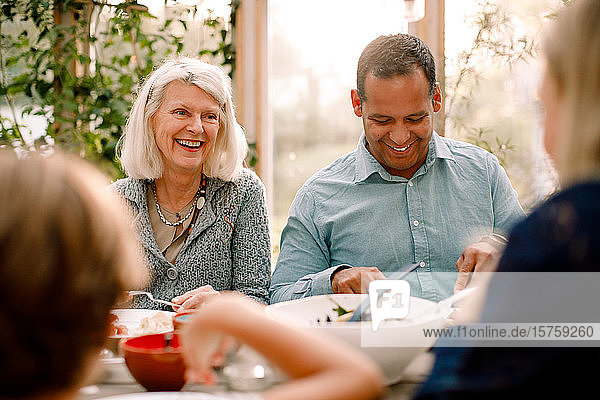 Smiling family enjoying meal while sitting at dining table during lunch