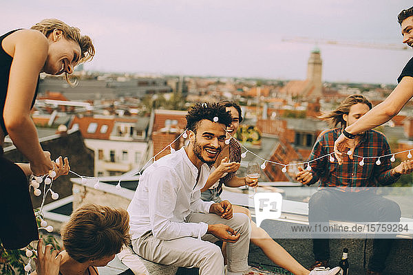 Verspielte Freunde genießen mit Schnurlicht auf der Terrasse während der Dachparty