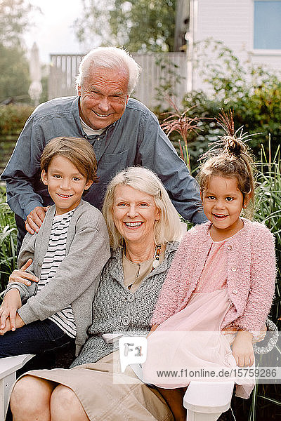 Porträt der Großeltern und Enkelkinder im Hinterhof sitzend